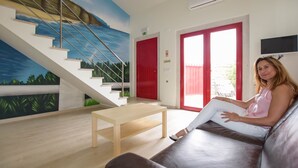 A modern interior with a staircase, a red door, and a person sitting on a couch. - Tia Malaca (Sintra)