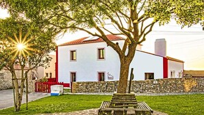 A white building with a red roof, a stone wall, and a bench in front. - Tia Malaca (Sintra)