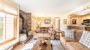 A cozy living room with a fireplace, a sofa, a coffee table, and a kitchen area in the background. - Two Private Balconies w/ Beautiful Views & Short Walk to Lifts, Shops, Dining (Keystone)
