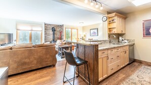 A modern kitchen with a bar area, wooden cabinets, and a stone accent wall. - Two Private Balconies w/ Beautiful Views & Short Walk to Lifts, Shops, Dining (Keystone)