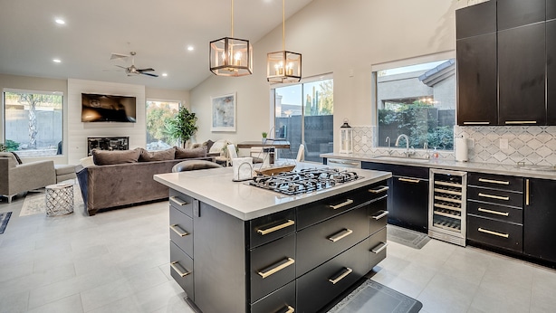 A modern kitchen with a central island, dark cabinetry, and a large window providing natural light. - Recently Renovated Luxury Home in Grayhawk (Scottsdale)