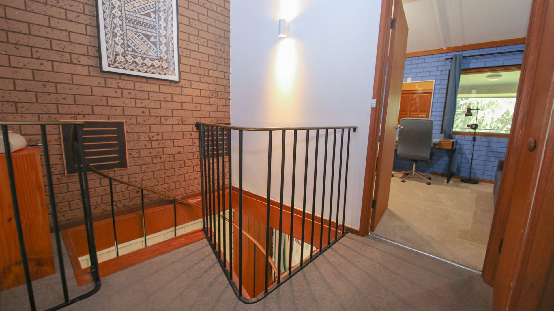 Eine Treppe mit Metallgeländer führt zu einem Raum mit blauer Wand und einem Fenster.