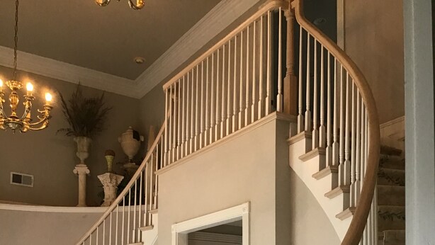 A grand staircase with a wooden handrail and white balusters, leading to an upper floor.