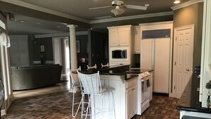 A kitchen with a herringbone floor pattern, white cabinetry, a central island with bar stools, a built-in microwave, and a stove.