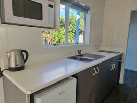 A compact kitchen with a microwave, sink, and a Hisense refrigerator.