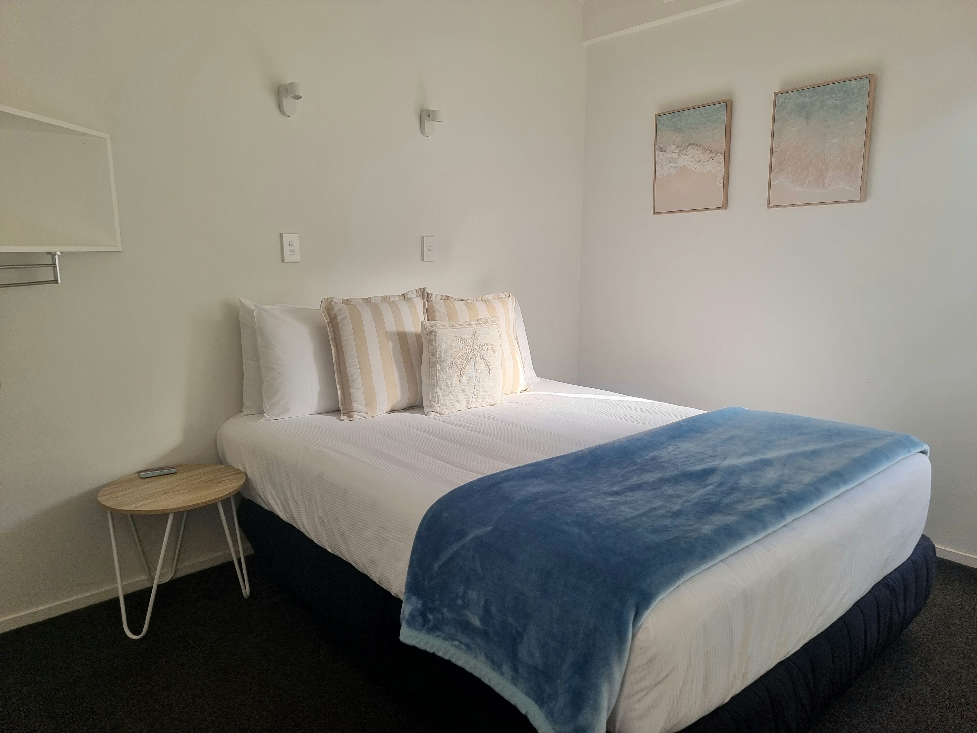 A bedroom with a bed, a small side table, and two wall-mounted light fixtures.