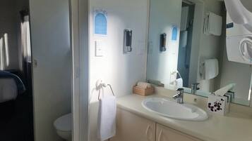Ein Badezimmer mit Waschbecken, Spiegel, Handtuchhalter und einer kleinen Holzkiste.