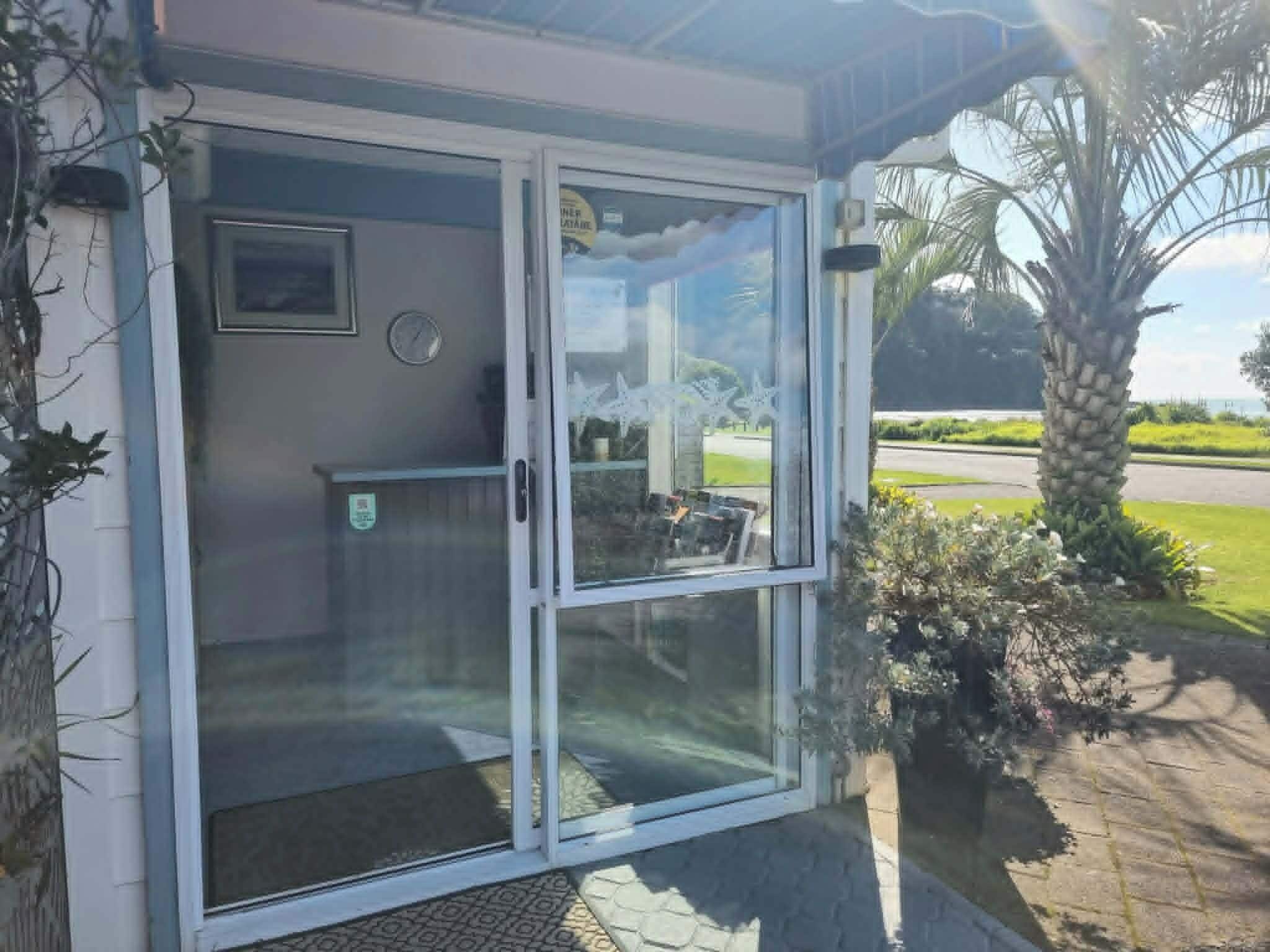 A glass door entrance with a clock and a small framed picture on the wall.