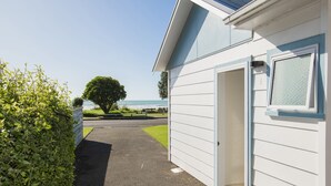 A pathway leading to a white building with a view of the sea. - Ohope Beach Motel (Ohope)