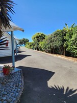 A quiet street lined with lush greenery and a white building with a covered porch.