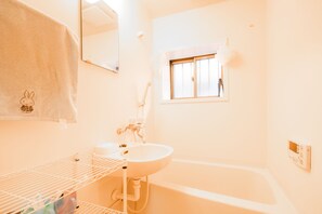 A bathroom with a white sink, a mirror, a window, and a towel rack with a towel. - Sakuragawa no Waho House (Osaka)