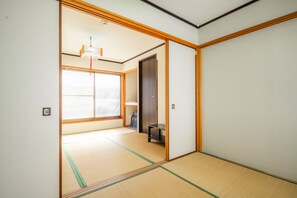 A traditional Japanese room with tatami flooring, a sliding door, and a small shelf. - Sakuragawa no Waho House (Osaka)
