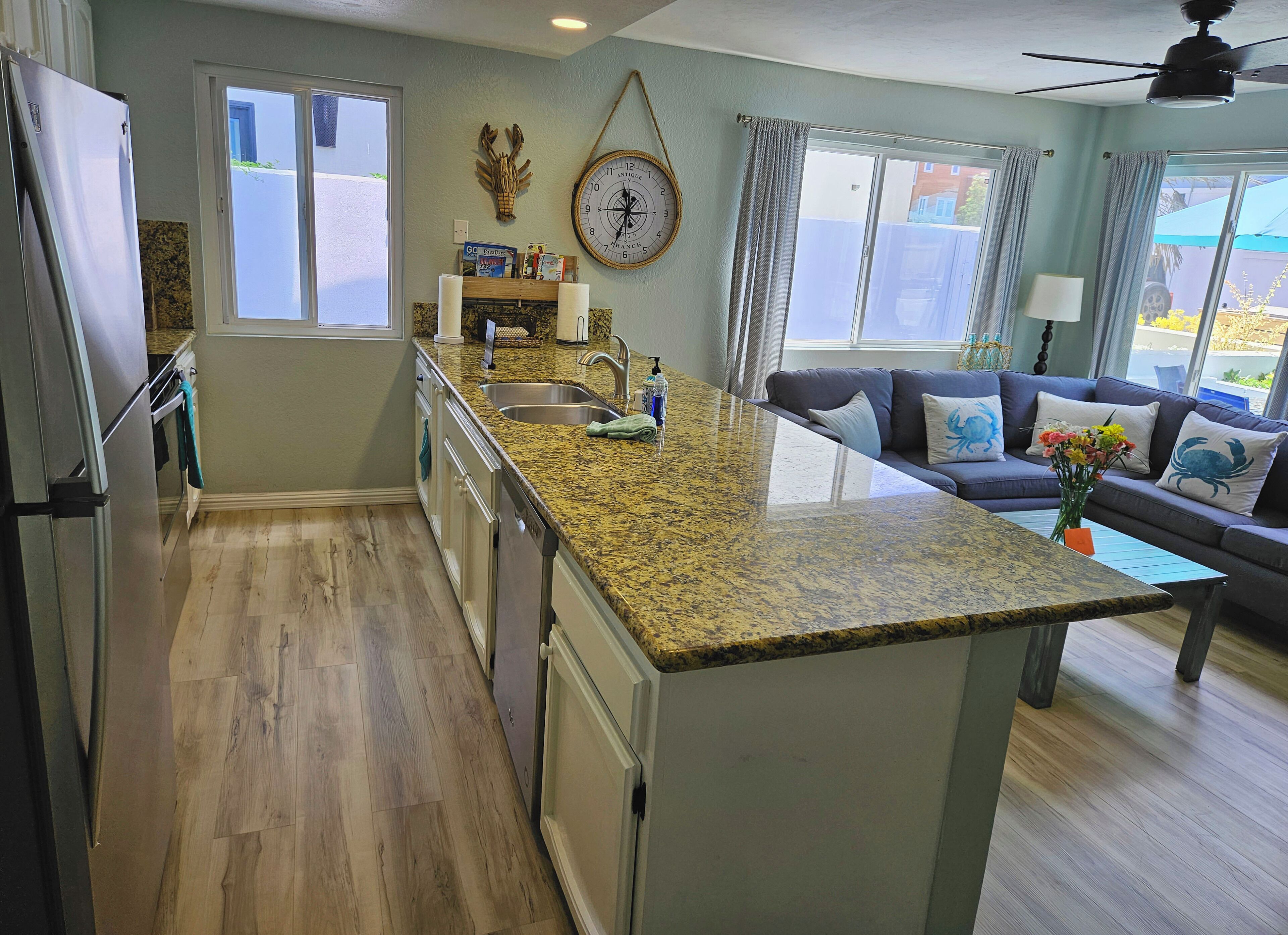 A modern kitchen with granite countertops, a built-in island, and a dining area with a sofa and table.