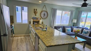 A modern kitchen with granite countertops, a built-in island, and a dining area with a sofa and table. - Luna Azul, only steps to Mission Beach! Free Wireless Internet / NO SMOKING (San Diego)