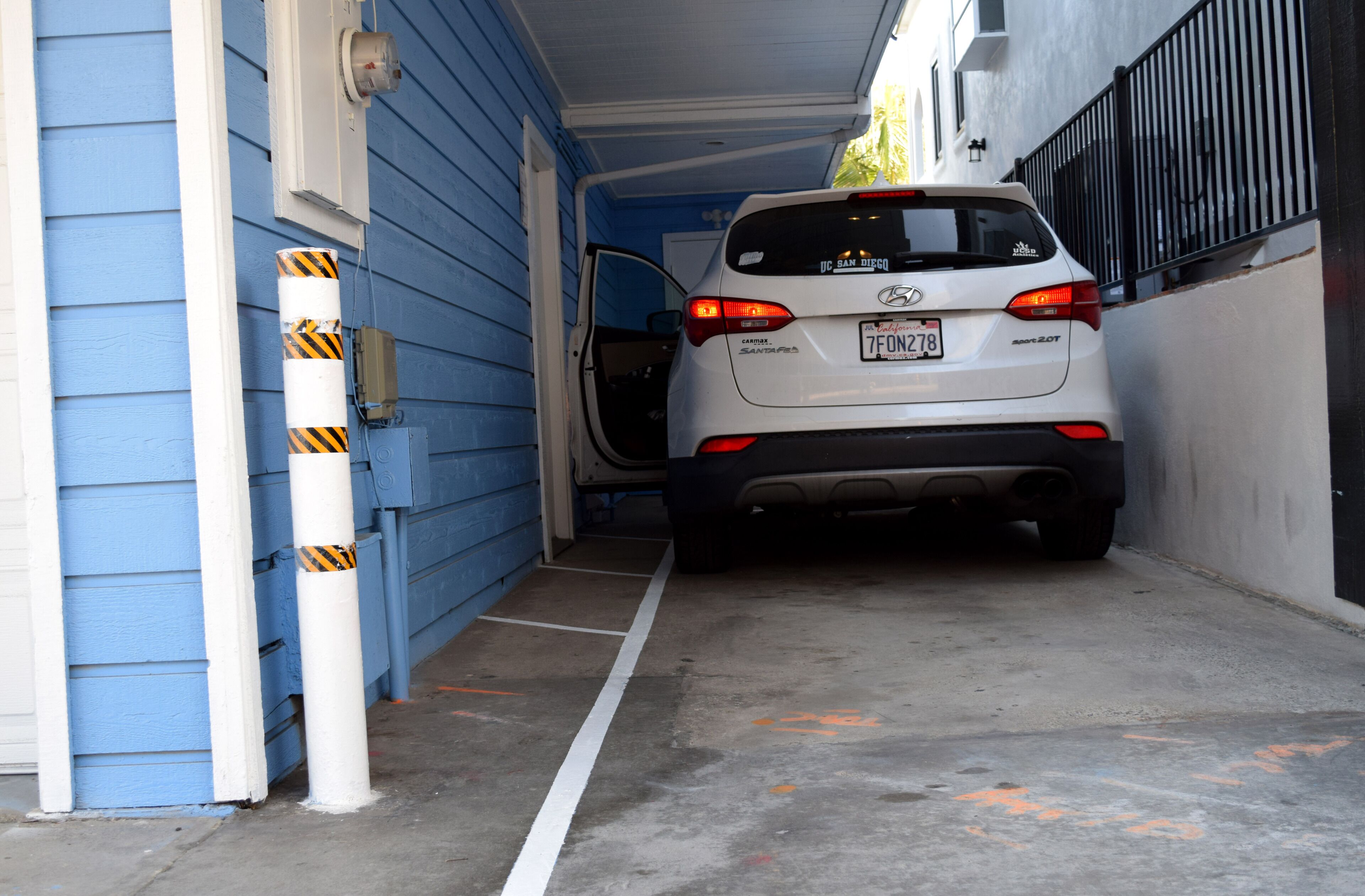 A white car parked inside a garage with a blue exterior wall.