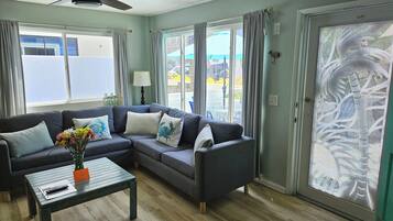 A living room with a grey sectional sofa, a coffee table, and a ceiling fan.