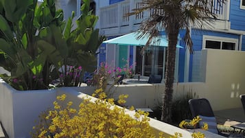 A modern building with a balcony, large potted plants, and outdoor seating.