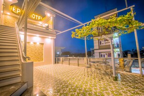 Ein Hotel Eingang mit Treppe, einer gefliesten Terrasse und Außenbestuhlung.