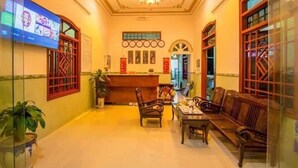 Un hall d’entrée avec un comptoir de réception, des meubles en bois et un lustre.