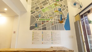 Een bar met een houten tafel en zwarte krukken, een kaart aan de muur en een plafondventilator.