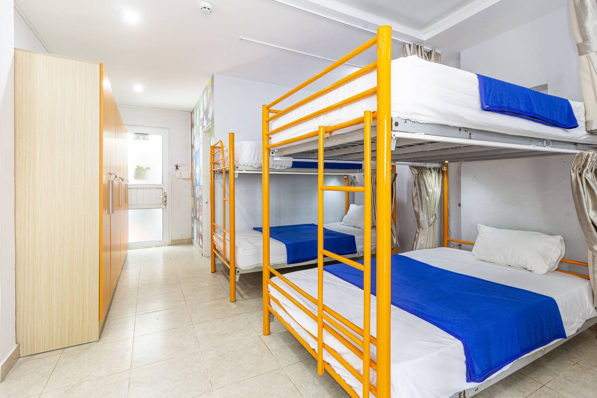 A dormitory room with bunk beds, a wardrobe, and a bathroom.