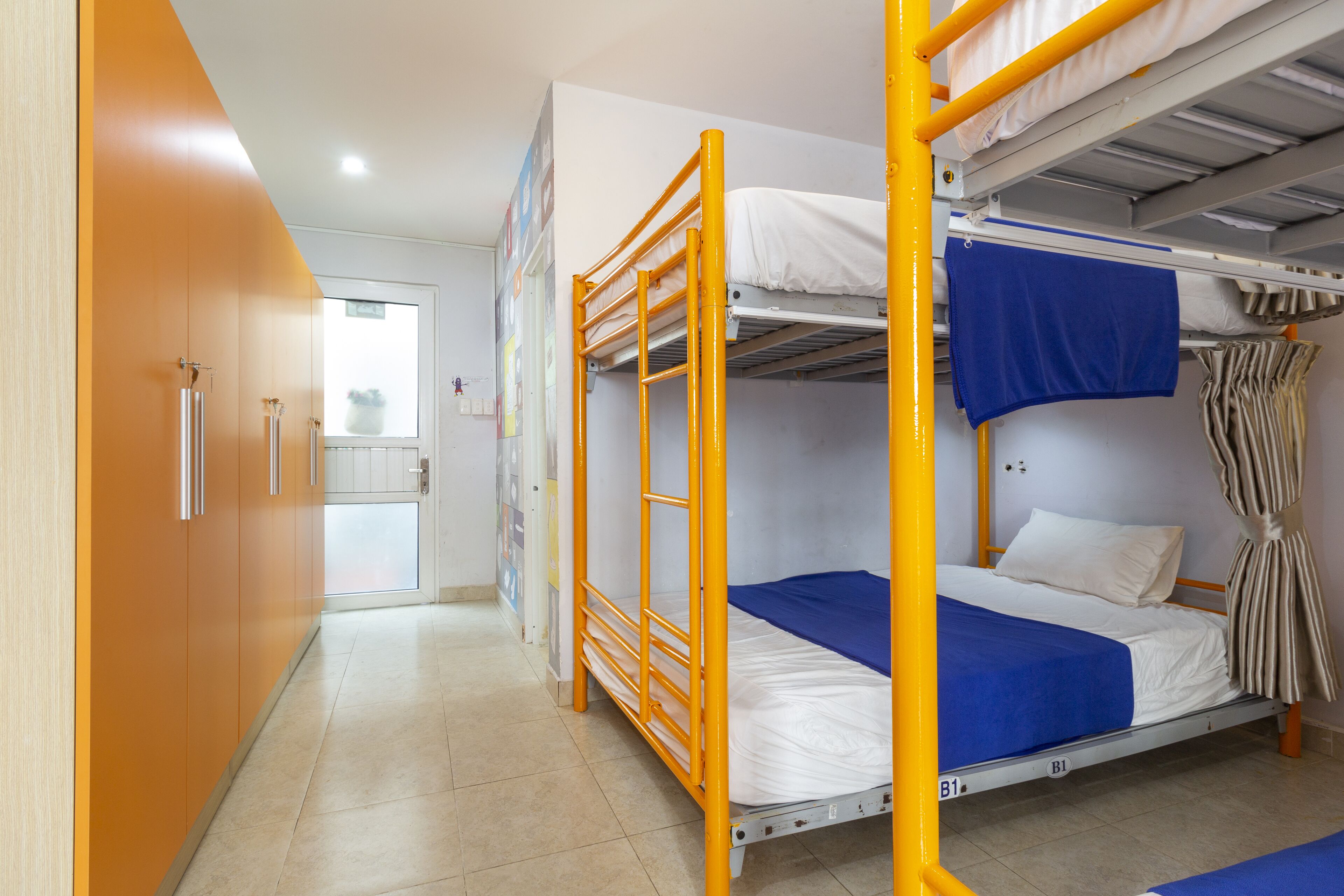 Une chambre de dortoir avec des lits superposés, une armoire et une porte donnant sur une salle de bain.