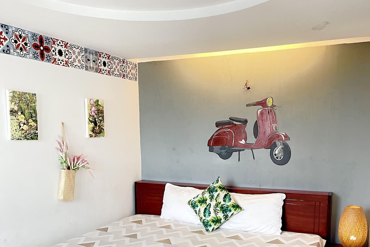 A neatly made bed with a patterned bedspread, a decorative pillow, and a bedside lamp.