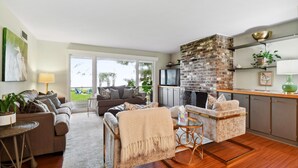 A spacious living area with a sofa, armchairs, a coffee table, and a fireplace. - Waterfront “State of Mind” vintage home.  (Bluffton)