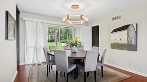 A dining area with a round table, grey chairs, a potted plant, and a painting on the wall. - Waterfront “State of Mind” vintage home.  (Bluffton)