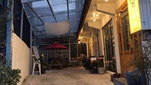 A covered outdoor area with a glass roof, potted plants, and a red umbrella. - Sudabang Guesthouse - Hostel (Mokpo)