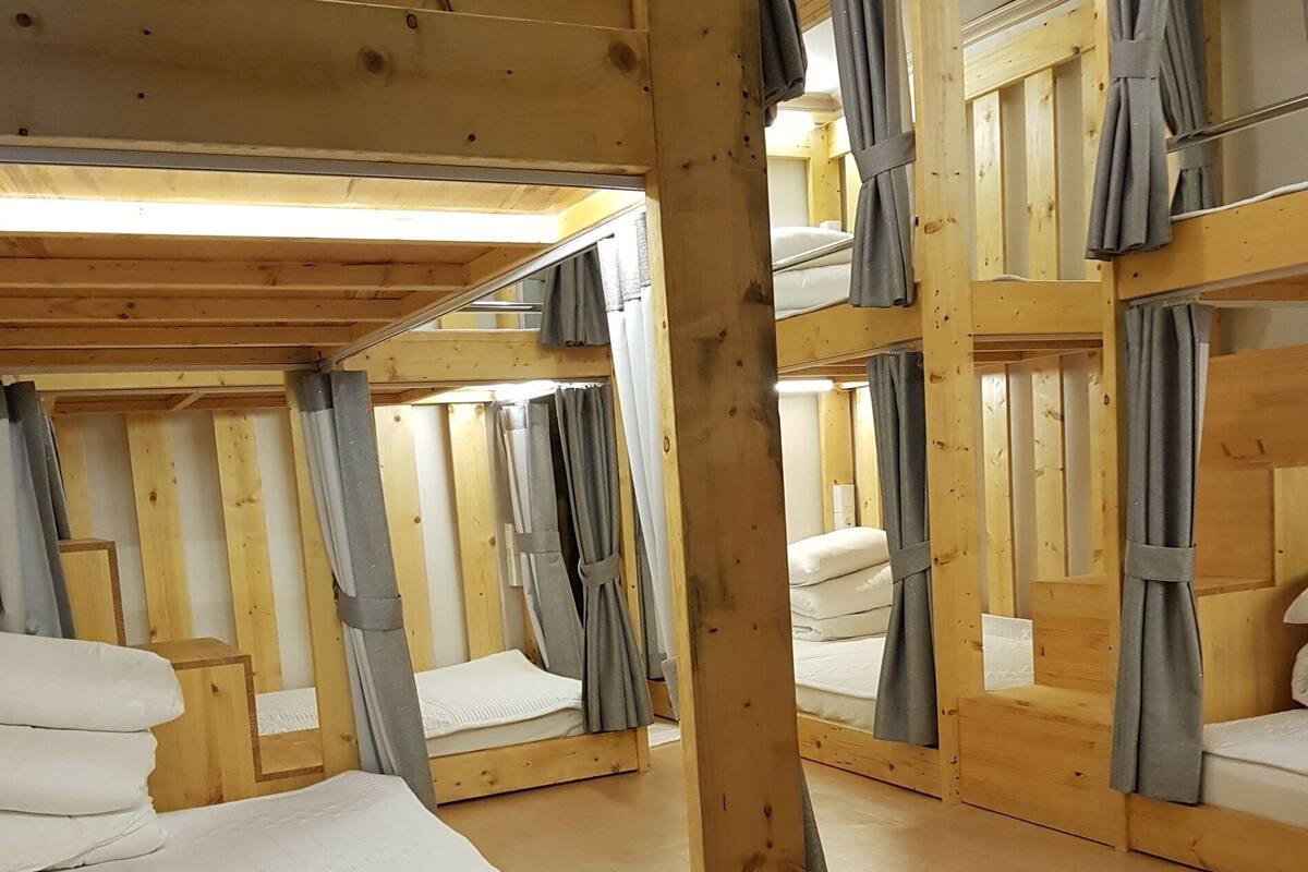 Una cabaña con literas, paredes de madera y cortinas.
