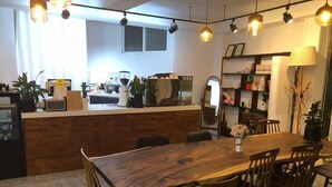 A modern kitchen with a wooden counter, a dining area with a wooden table and chairs, and pendant lighting. - Sudabang Guesthouse - Hostel (Mokpo)