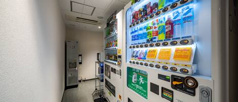 A vending machine with various beverages and snacks, a water dispenser, and a life line vending machine in a hallway.
