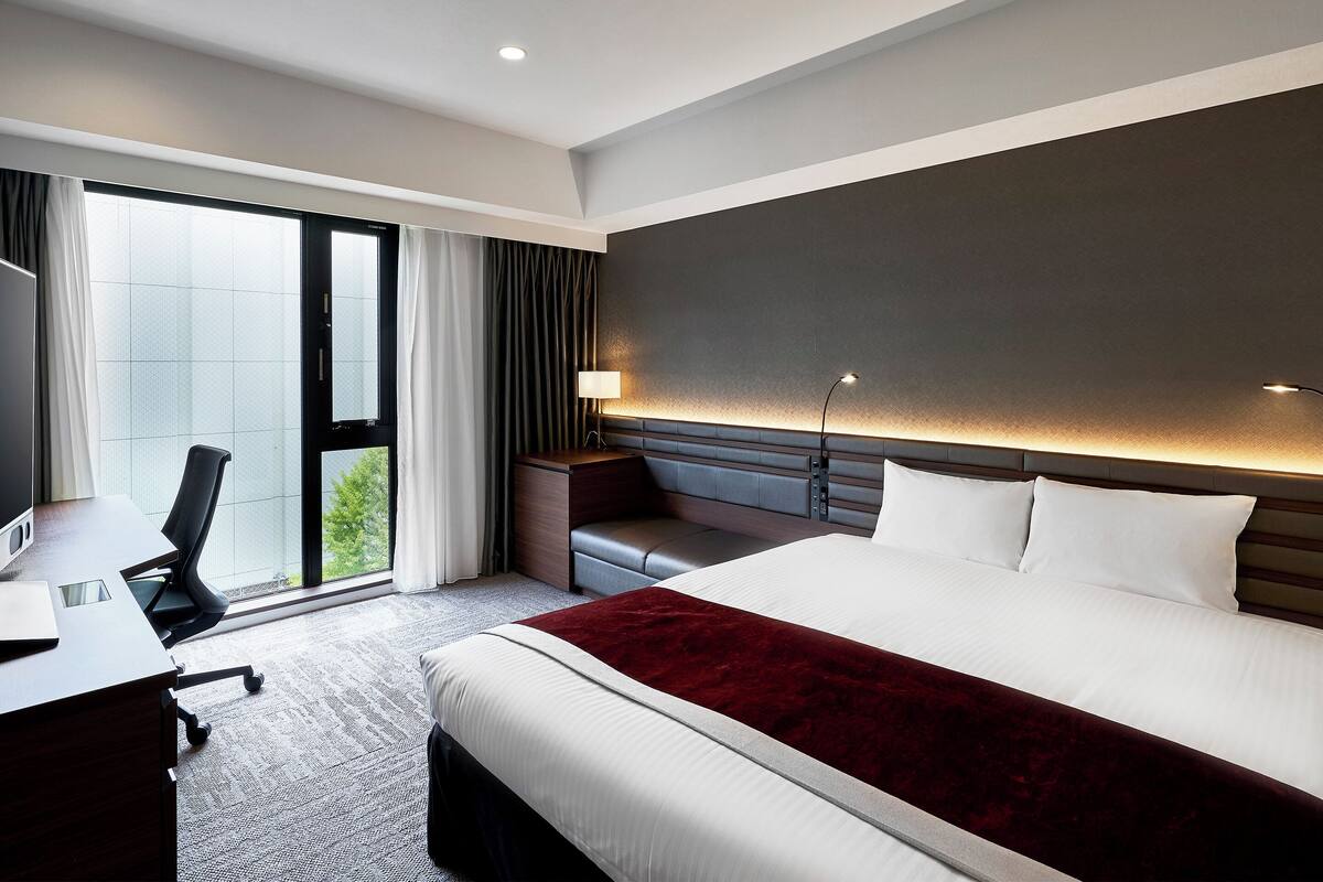 Una habitación de hotel moderna con una cama grande, un escritorio y una silla.