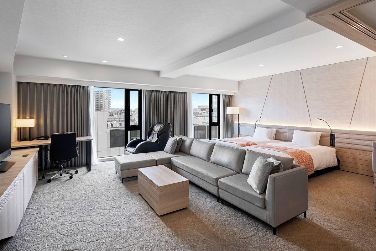 Una habitación de hotel moderna con una cama grande, un sofá, un escritorio y una silla.