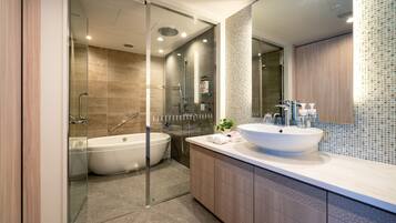 A modern bathroom with a glass shower enclosure, a freestanding bathtub, and a large sink with a mirror above it.