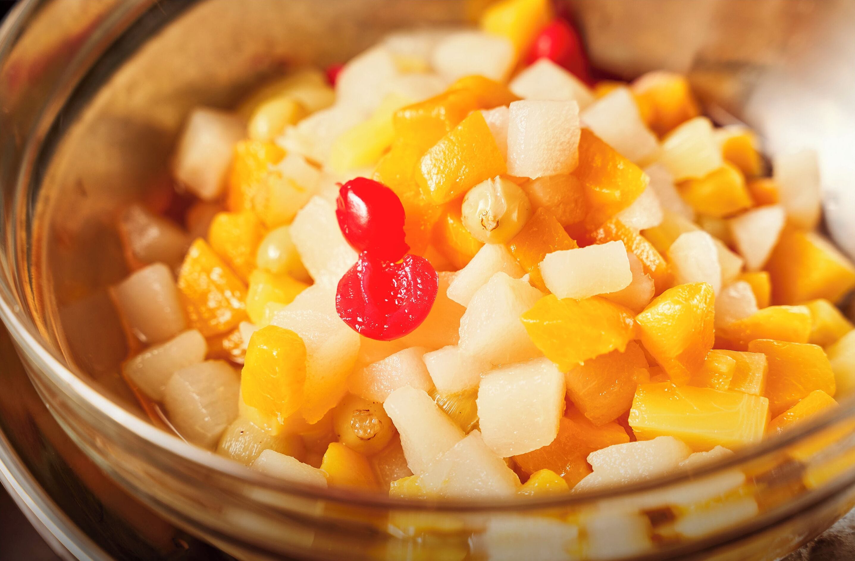A bowl of diced fruit with a red berry on top.