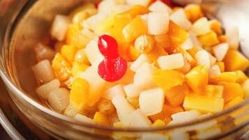 A bowl of diced fruit with a red berry on top.