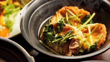 A close-up of a dish with salmon and greens in a black bowl.