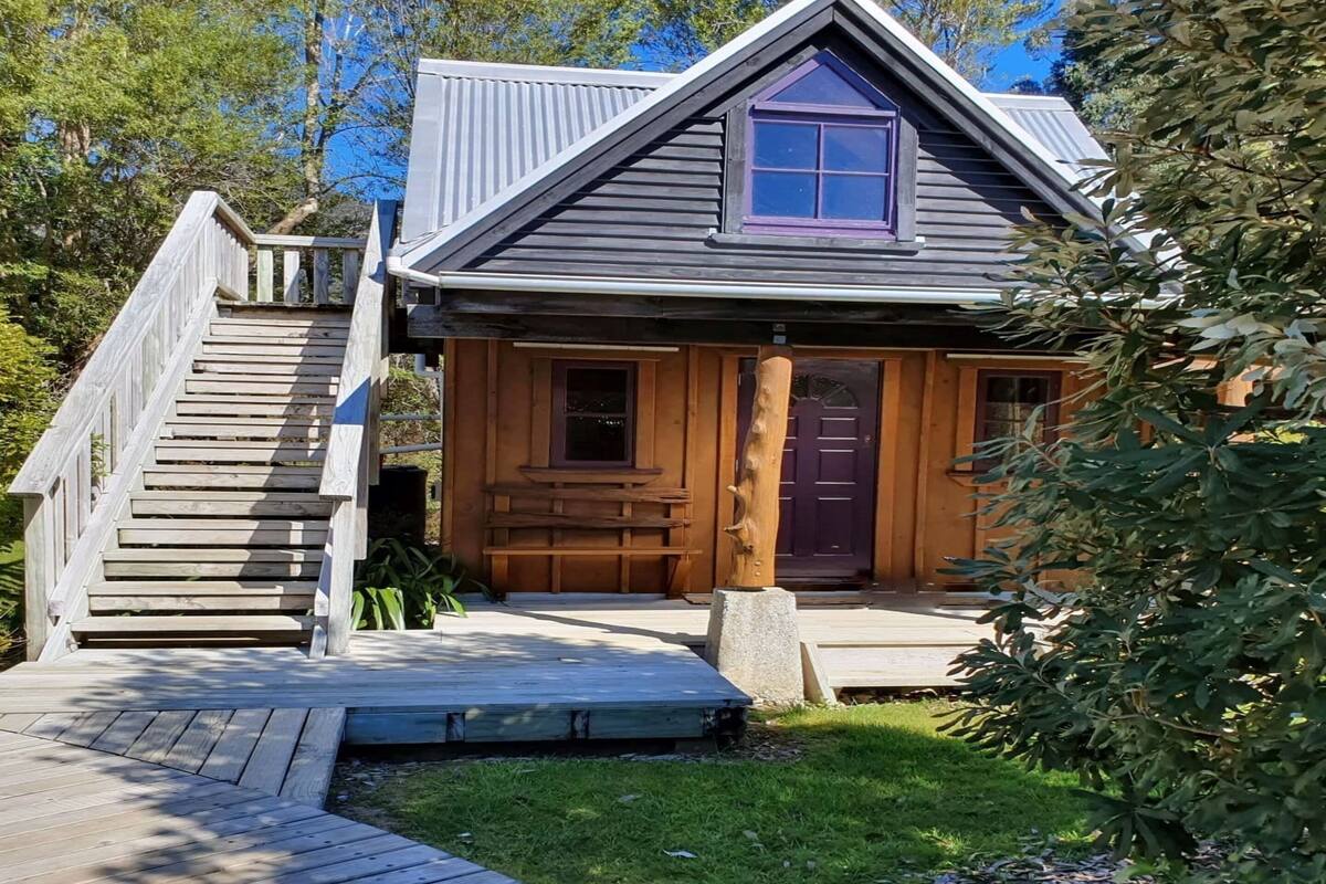 A cabin with a wooden exterior, a front porch, and a staircase leading to the entrance.