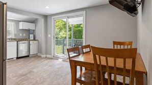 Een keuken met witte kasten, een vaatwasser en een eethoek met een houten tafel en stoelen.
