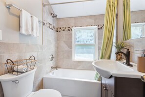 Et badeværelse med toilet, bidet, badekar og håndvask.