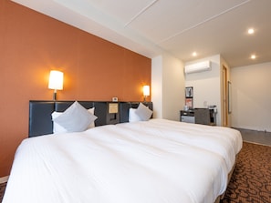 A hotel room with a large bed, two bedside lamps, a desk with a chair, and a small table with a coffee maker.