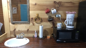 L’intérieur d’une cabane en bois comprend un évier, un miroir, une machine à café et un four à micro-ondes.