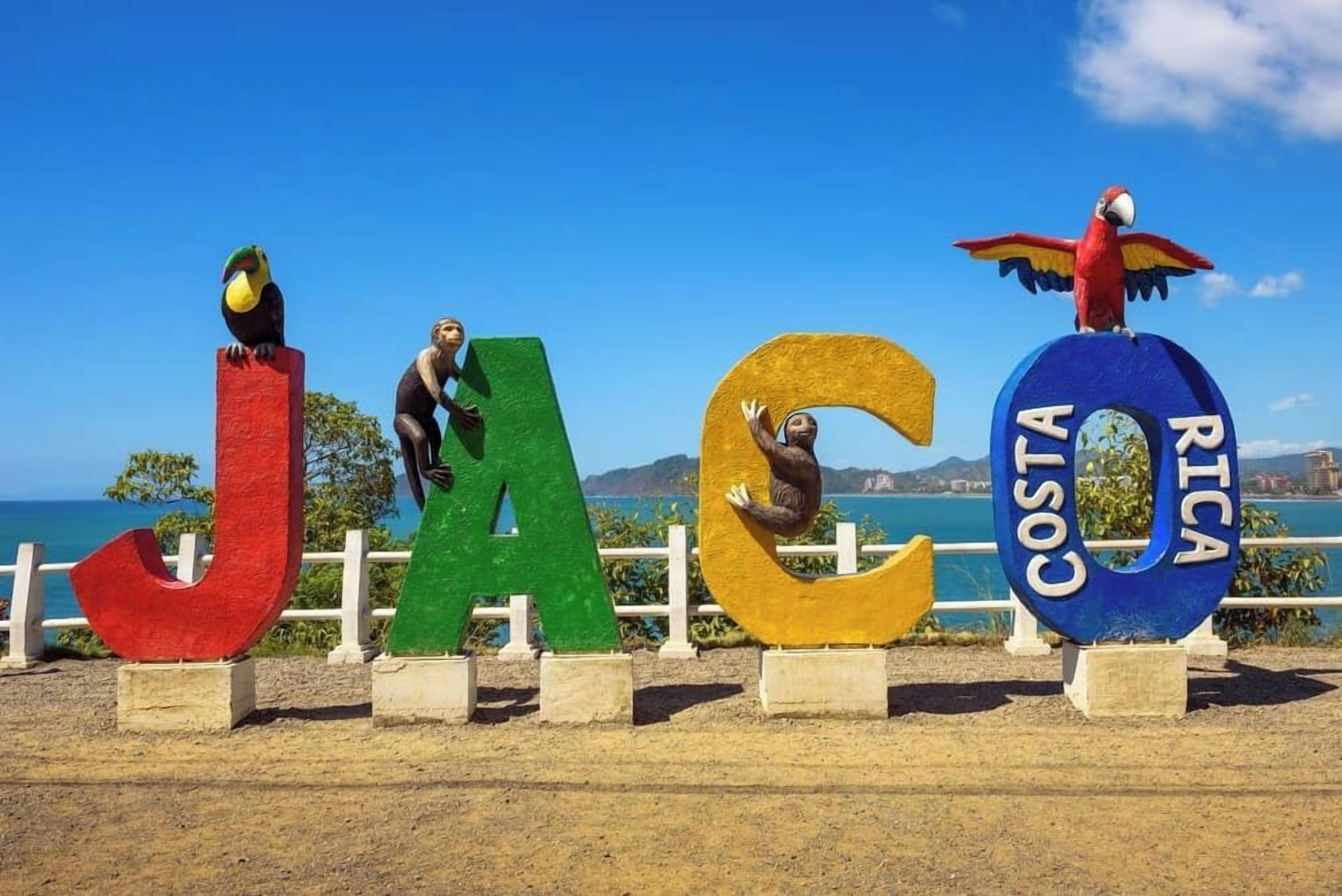 Large, colorful letters spelling "JACOTA RICA" with parrots perched on them, set against a coastal backdrop.