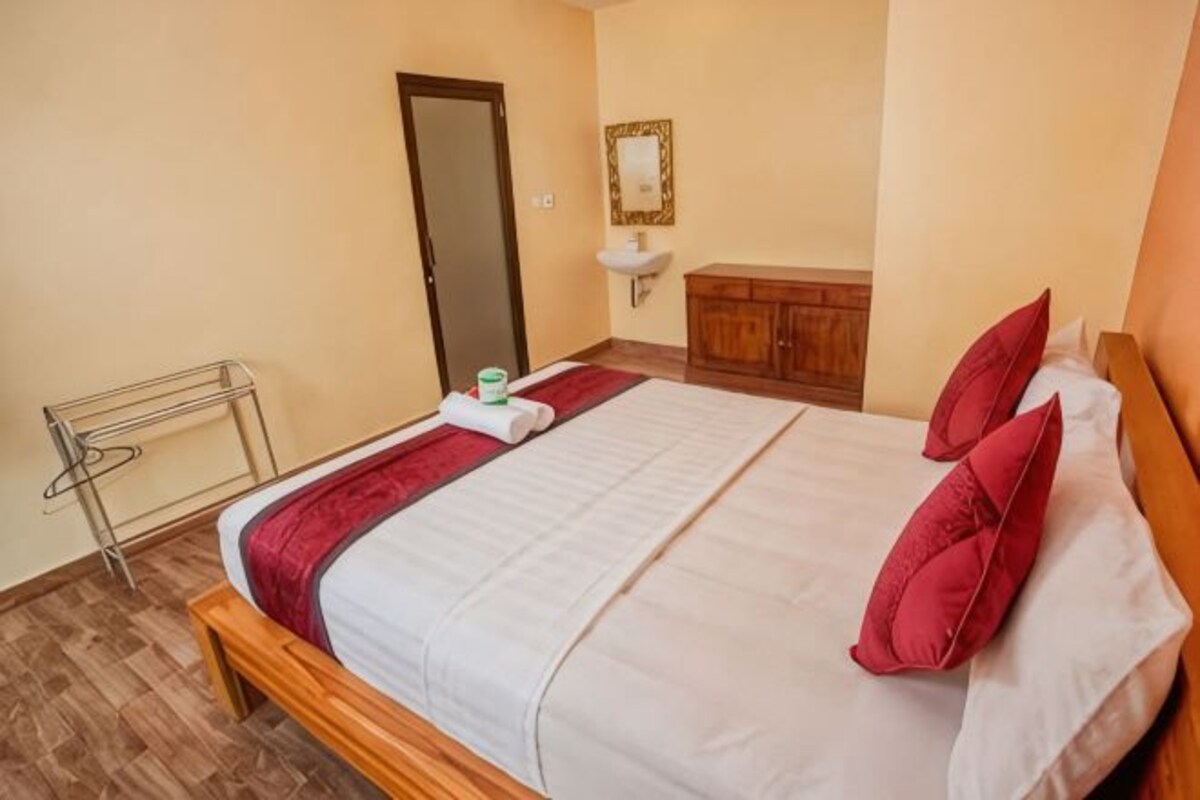 A bedroom with a bed, a wooden headboard, a bedside table, a mirror, and a wooden cabinet.