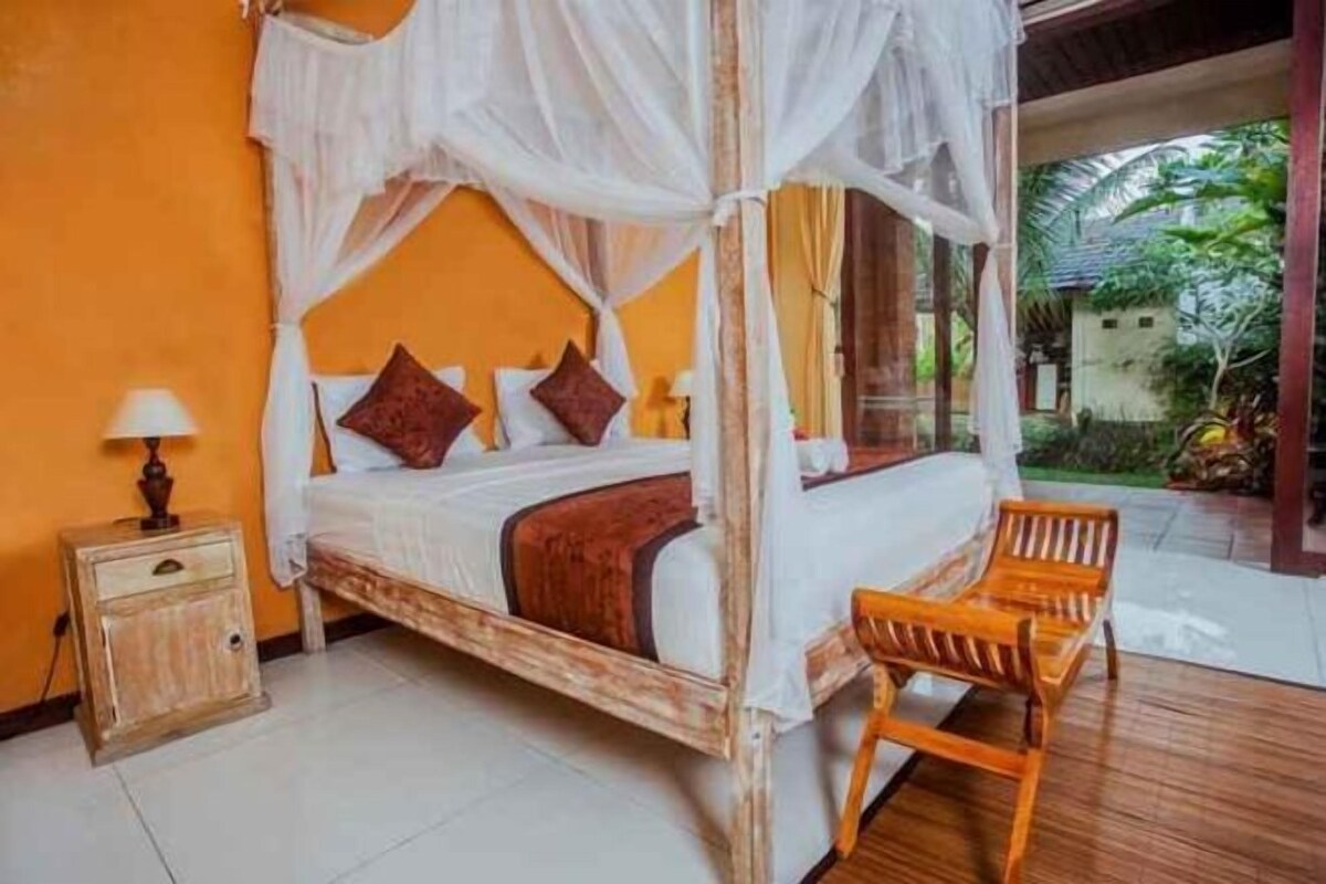 A room with a bed, bedside table, and a wooden bench.