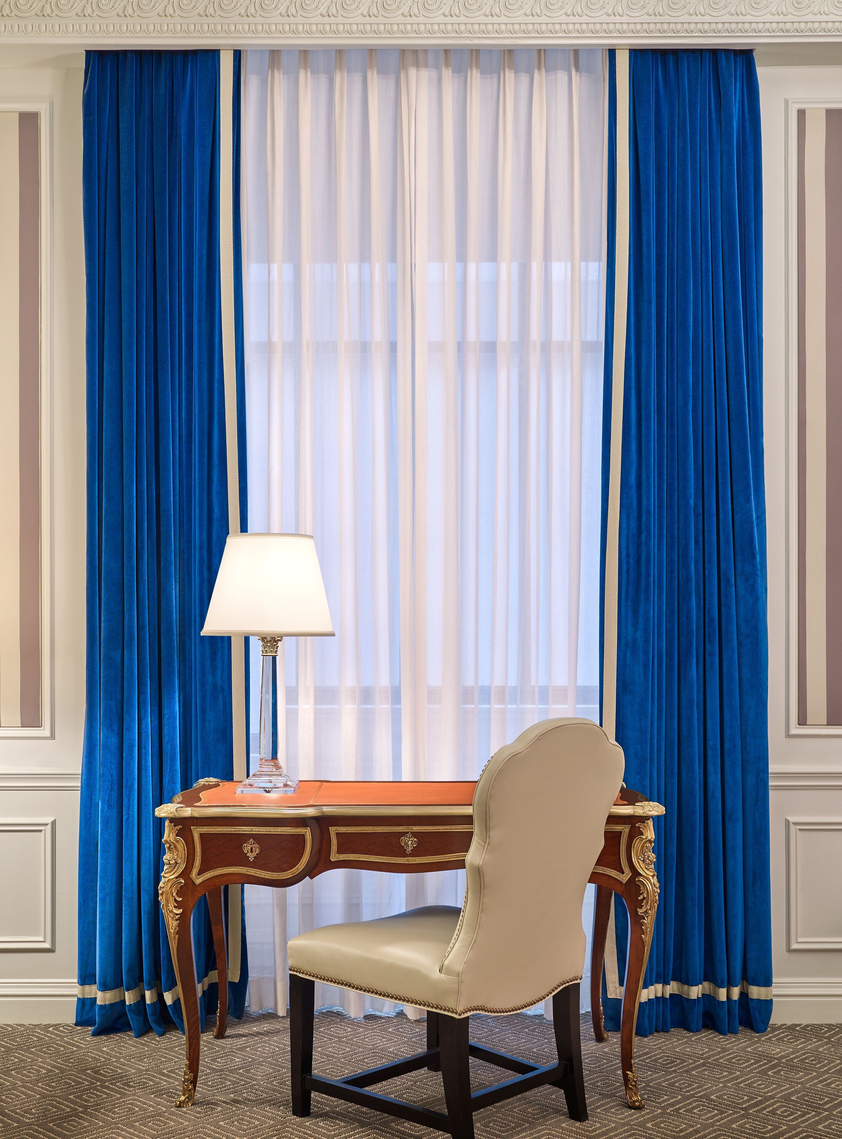 A room with a desk, chair, and a lamp.