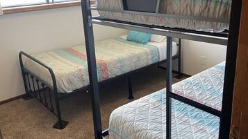 A bunk bed room with a window, carpeted floor, and a painting on the wall.