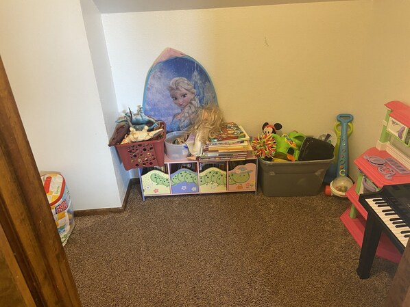 A child's play area with toys, a bookshelf, and a painting on the wall.